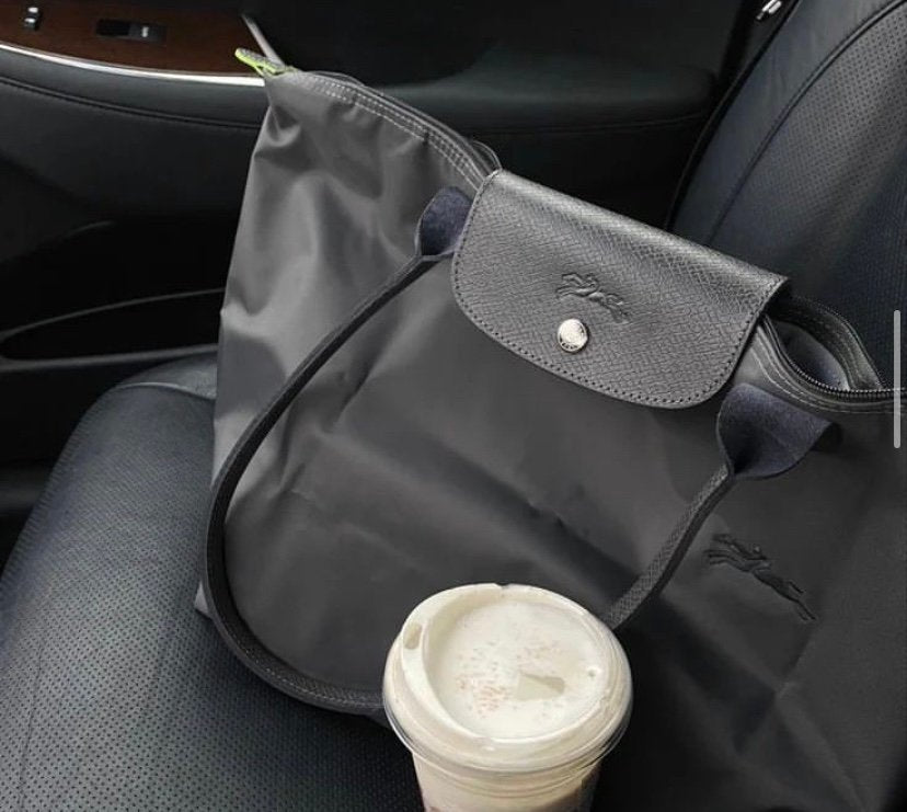 Longchamp Le Pliage Green M tote bag in black, showing the foldable design and durable fabric with black handles.